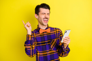 Poster - Photo of young handsome crazy excited man listen music in earphones hold cellphone isolated on yellow color background