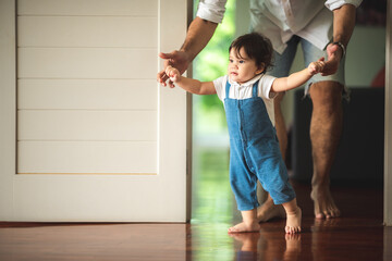 cute toddler little child family concept, baby learning to walk with father and mother to help care and holding hand, first step with childhood parent support, small love portrait little boy at home