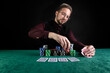 © Nataly - Young handsome poker player sitting at a green gaming table with a lot of chips and good cards.
