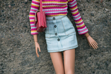 Wall Mural -  Closeup of mannequin doll wearing a mini blue jeans skirt, pink top and red handbag posing in the street