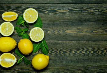 Wall Mural - lemons with mint leaves on a dark wooden background   photographed from above in the form of a frame