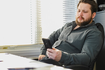 Wall Mural - Successful business director sitting and using smartphone in office.
