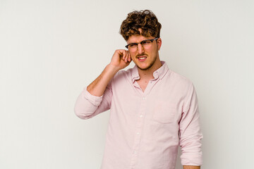 Wall Mural - Young caucasian man isolated on white background covering ears with fingers, stressed and desperate by a loudly ambient.