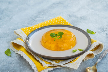 Wall Mural - Dessert, orange jelly on a ceramic plate on a light concrete background.