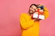 © denis_vermenko - Cheerful smiling african american man holding wrapped present boxes. Happy black young man congratulating, giving birthday gift, isolated on pink background.