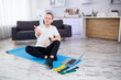 © DSMT - The man goes in for sports at home. Athlete drinks water while sitting on the floor at home, healthy lifestyle