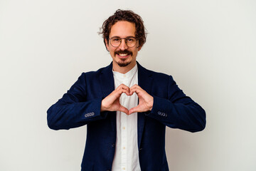 Young business man isolated on white background smiling and showing a heart shape with hands.