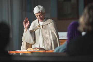 Senior priest reading the Bible for people during ceremony in the church