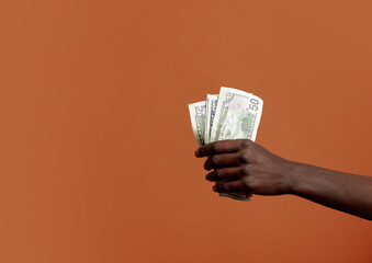 Wall Mural - Black female hand hold dollars on orange background