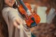 © Kiryakova Anna - A beautiful girl with a violin in her hands among the autumn orange foliage in the forest and with music sheets in the background. Girl stretches the violin bow forward