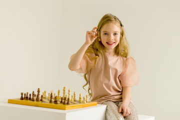 The little girl holds a chess piece in her hand.