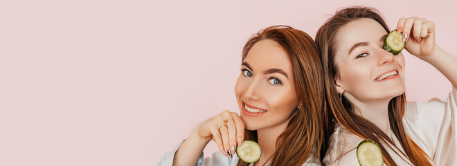 Wall Mural - two girls make homemade face beauty masks. cucumbers for the freshness of the skin around the eyes. 