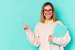 © Asier - Young student woman holding books isolated on blue background smiling and pointing aside, showing something at blank space.