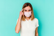 © Asier - Young woman wearing a mask for virus isolated on blue background pointing temple with finger, thinking, focused on a task.
