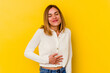 © Asier - Young caucasian skinny woman isolated on yellow background touches tummy, smiles gently, eating and satisfaction concept.