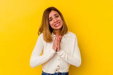 Young caucasian skinny woman isolated on yellow background holding hands in pray near mouth, feels confident.