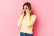 © Asier - Young caucasian woman isolated on pink background blink through fingers frightened and nervous.