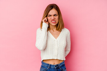 Wall Mural - Young caucasian woman isolated on pink background covering ears with hands.