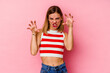 © Asier - Young caucasian woman isolated on pink background showing claws imitating a cat, aggressive gesture.