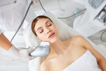 Woman getting facial lifting therapy in beauty salon