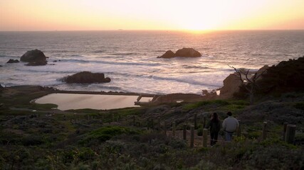 Wall Mural - Couple rushing to watch the beautiful sunset by the ocean