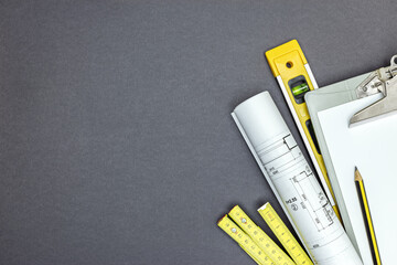 Wall Mural - clip board with blank paper, roll of blueprint and measure tools on grey background. home improvement concept. top view