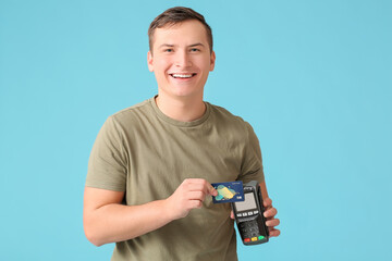 Wall Mural - Young man with payment terminal and credit card on color background