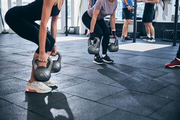 Strong ladies doing a weight-lifting exercise indoors