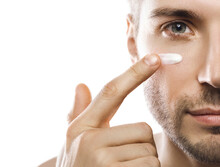 Men's Beauty. Young Man Is Applying Moisturizing And Anti Aging Cream On His Face