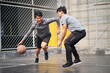 © imtmphoto - two young asian men playing basketball outdoors
