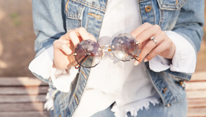 Wall Mural - Young woman holding sunglasses in outdoors.