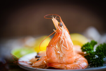 fresh shrimps served on plate in the seafood restaurant dark background, boiled shrimp prawns cooked with herbs and spice