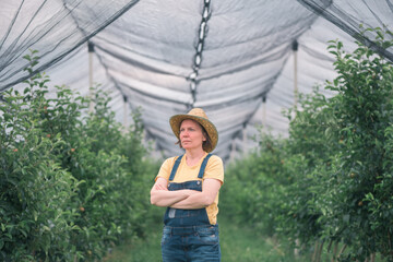 Wall Mural - Portrait of female farmer posing in apple fruit orchard