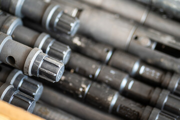 Wireline logging downhole tool, equipment for oil well intervention operation with thread protector covered, stack in the wooden box for transportation. Industrial object photo. Selective focus.