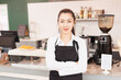 © Chaiya - Beautiful Asian barista woman crossed arms and stands to welcome customers with copy space in cafe coffee shop