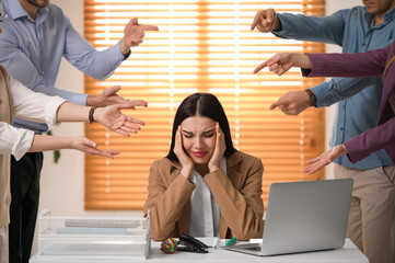 Wall Mural - Coworkers bullying their colleague at workplace in office, closeup