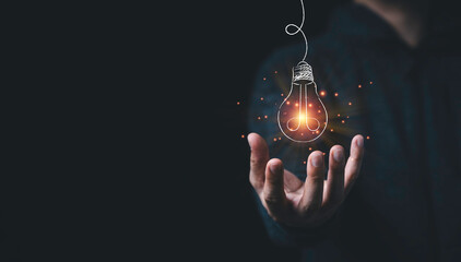 Fototapete - Man hand holding hanging glowing drawing light bulb with orange rays , creative thinking idea and innovation concept.