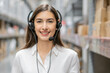© SOLO PLAYER - Portrait of smiling warehouse woman staff listening and talking to customer with headset working in distribution factory. female call center or support operator working for online shopping.