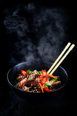 Poster - Stir fry soba noodles with beef and vegetables in wok on dark background, Asian noodles with beef WOK in black bowl