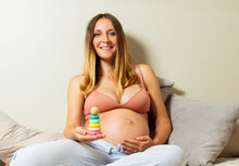 Smiling Pregnant Woman Image Holding Pyramid Toy