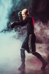 Wall Mural - Sportsman boxer fighting on black background with smoke. Boxing