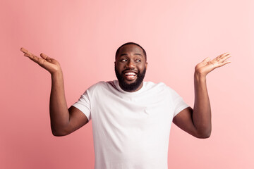 Wall Mural - Portrait of clueless funny guy raise hands look side empty space on pink wall