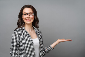 Young woman smiling and gesturing to copy space.