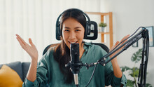 Happy Asia Girl Record A Podcast With Headphones And Microphone Look At Camera  Talk And Take A Rest In Her Room. Female Podcaster Make Audio Podcast From Her Home Studio, Stay At House Concept.