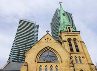 Wall Mural - Old church steeple against the cloudy sky and high rise modern buildings