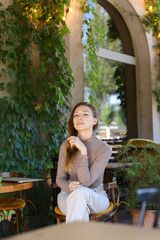 Wall Mural - Young european woman posing at street cafe, closed laptop computer on table.