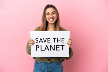 Wall Mural - Young caucasian woman isolated on pink background holding a placard with text Save the Planet with happy expression