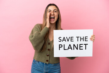 Wall Mural - Young caucasian woman isolated on pink background holding a placard with text Save the Planet and shouting