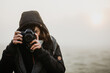 Junge Fotografin im Nebel. Kamera bedeckt einen Teil des Gesichts. 