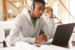 © Wavebreak Media - Stressed african american young man wearing headphones using laptop while studying at home